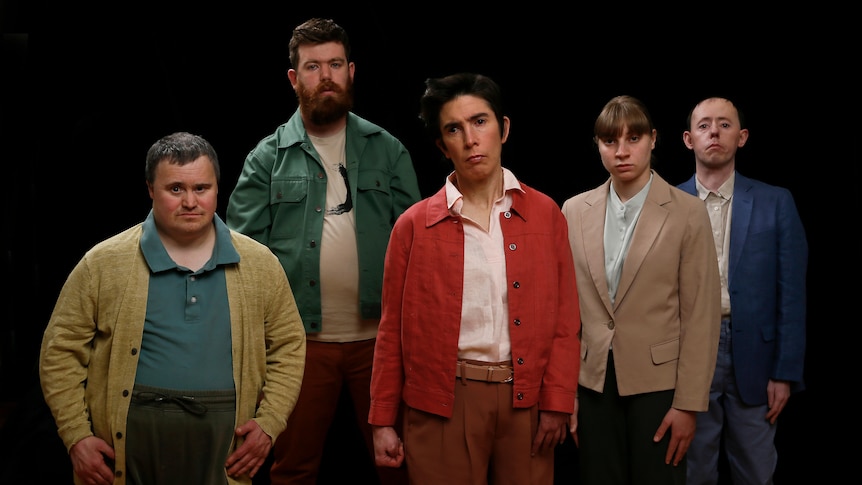 The five members of the Back to Back Theatre ensemble stand staggered facing the camera with serious expressions.