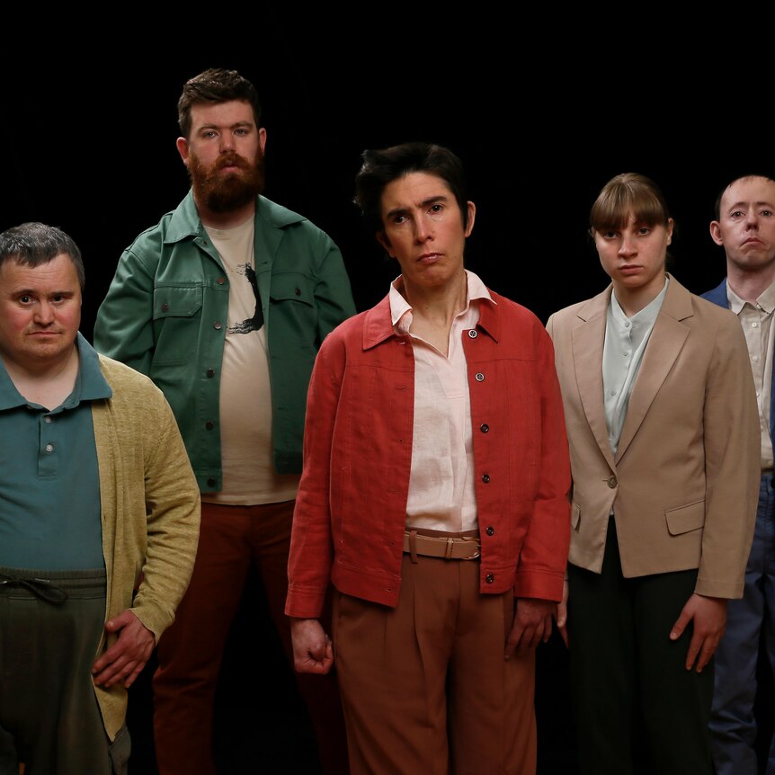 The five members of the Back to Back Theatre ensemble stand staggered facing the camera with serious expressions.
