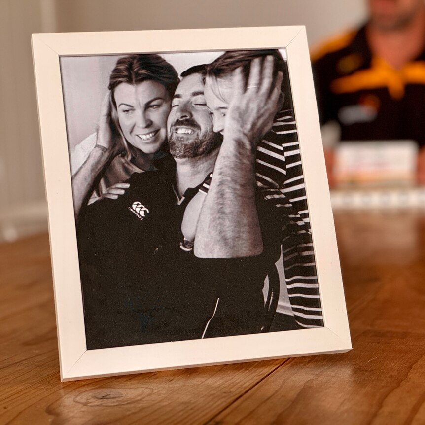 A photo on a table features a man and two children embracing.