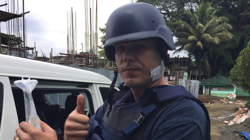 ABC correspondent Adam Harvey gives thumbs up after being treated for bullet injury to the neck