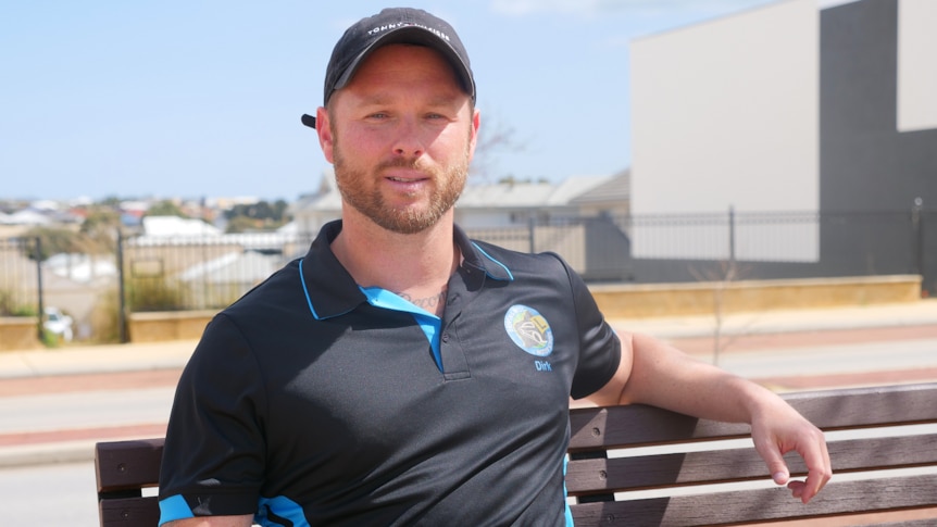 A man in a work shirt sits on a bench