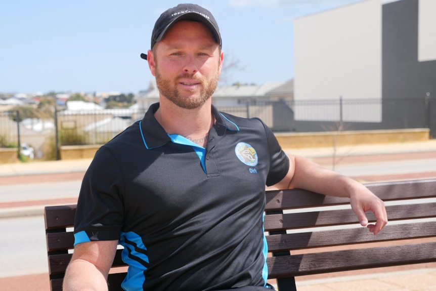 A man in a work shirt sits on a bench