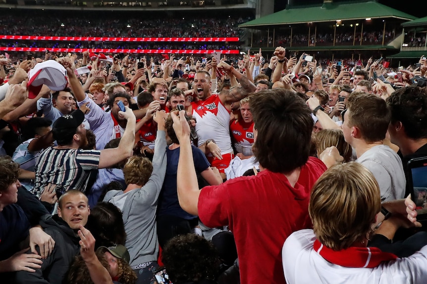 Lance Franklin is held aloft by a sea of people who have run on to the SCG