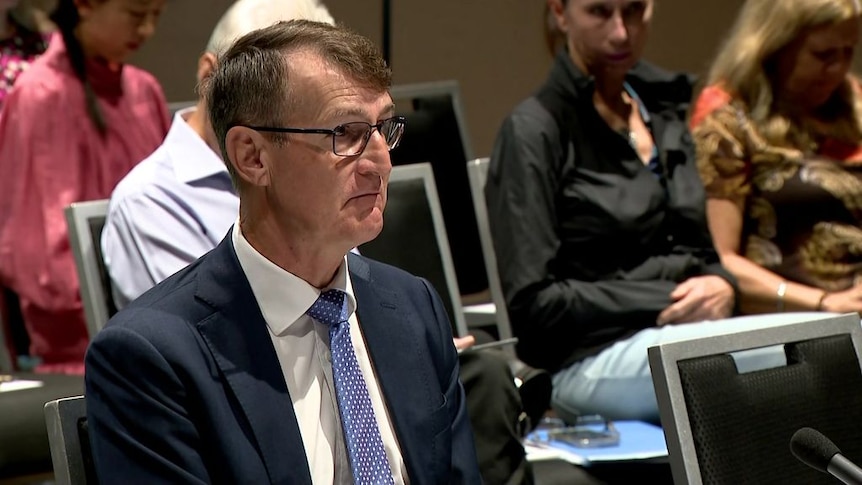 Graham Quirk sits in front of a microphone.