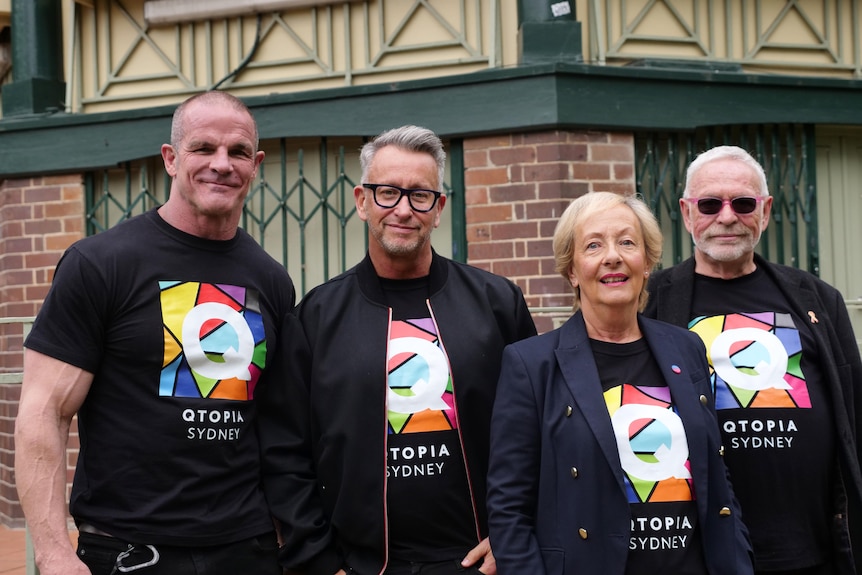 Four people wearing black t shirts smiling