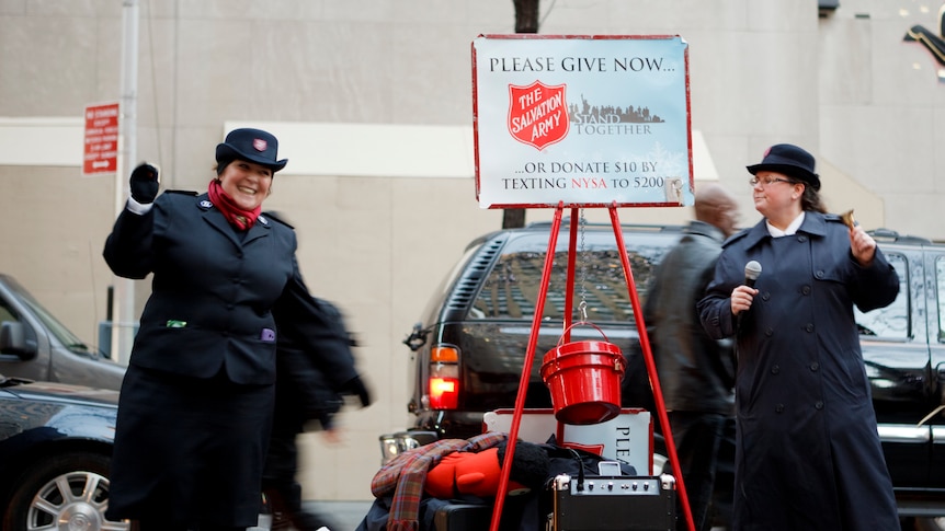 Two smiling Salvation Army officers collecting for charity on a city street