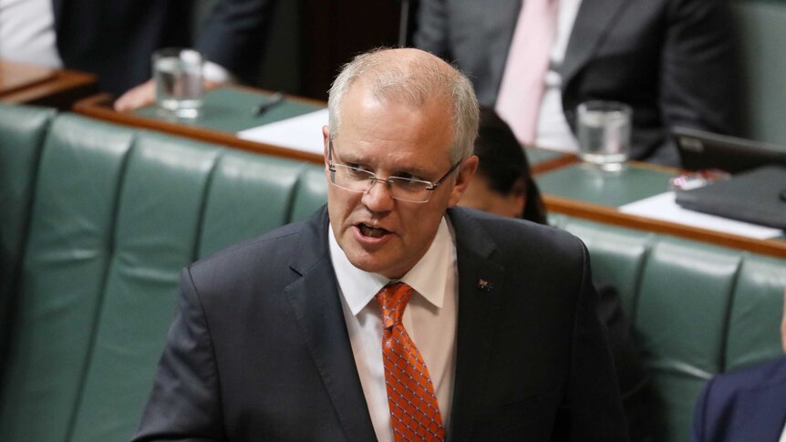 Scott Morrison wears a suit and an orange tie addresses parliament