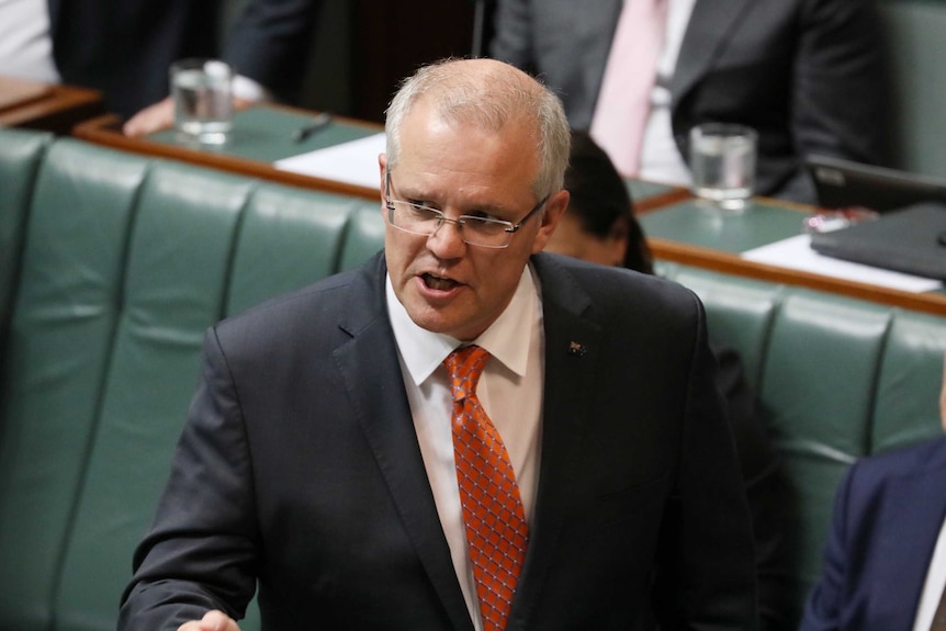 Scott Morrison wears a suit and an orange tie addresses parliament