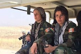 Two female Kurdish soldiers sit in the back of a truck