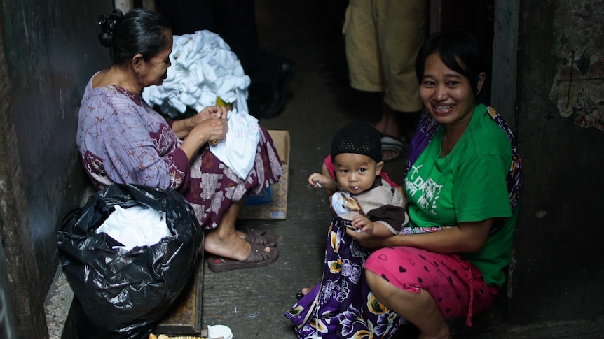 Woman holds up child in alleyway in Tambora slum in Indonesia.