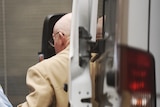Back view of Roger Rogerson being led from a prison van to an exterior door of the court.