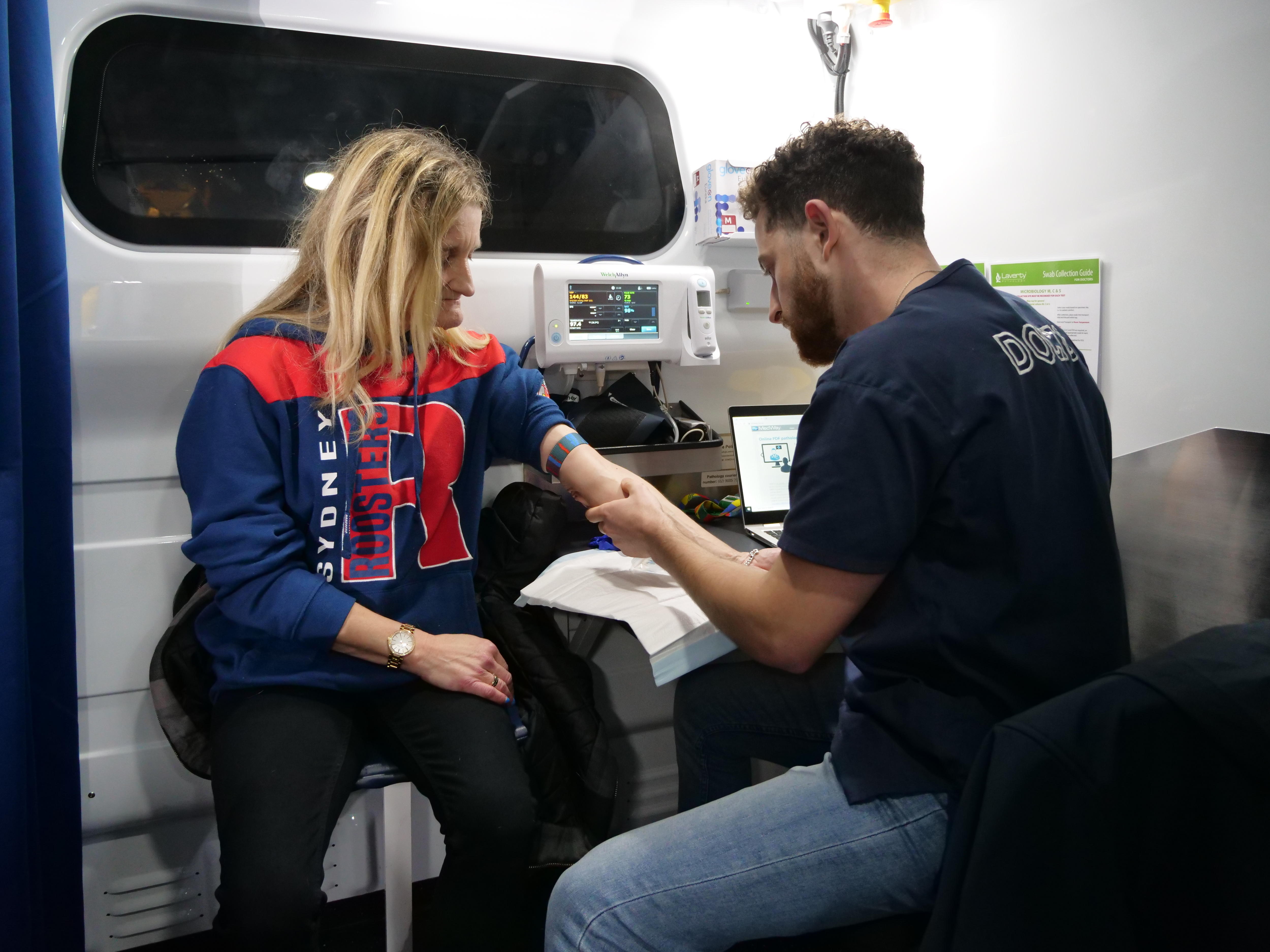 A woman holds her arm out as a man looks at it.