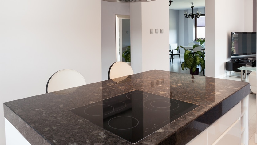 A generic photo of a shiny stone kitchen bench in a modern home.