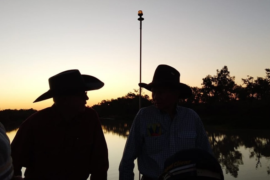 two people wearing cowboy hats overlooking a flooded river