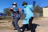 Two men pose for a photo in Wilcannia, one wearing personal protective equipment 
