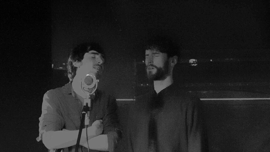 Grainy black-and-white image of brothers Brian and Diarmuid Mac Gloinn singing in a studio