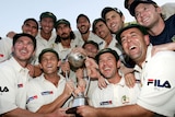 The Australia team holds a large trophy and smiles