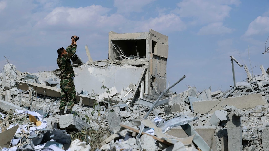 A Syrian soldier films the damage of the Syrian Scientific Research Centre.