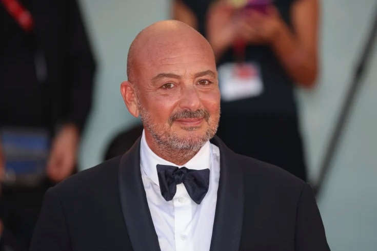 Director Emanuele Crialese wearing a suit and smiling at the camera