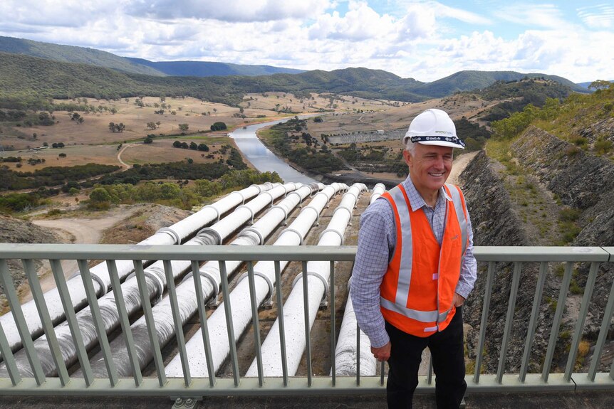 Malcolm Turnbull, wearing a hard hat and high-vis vest, stands in front of the Snowy Hydro Scheme