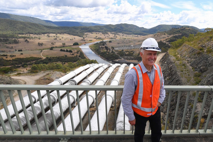 Malcolm Turnbull, wearing a hard hat and high-vis vest, stands in front of the Snowy Hydro Scheme