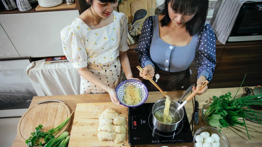 Mid shot of two people cooking food