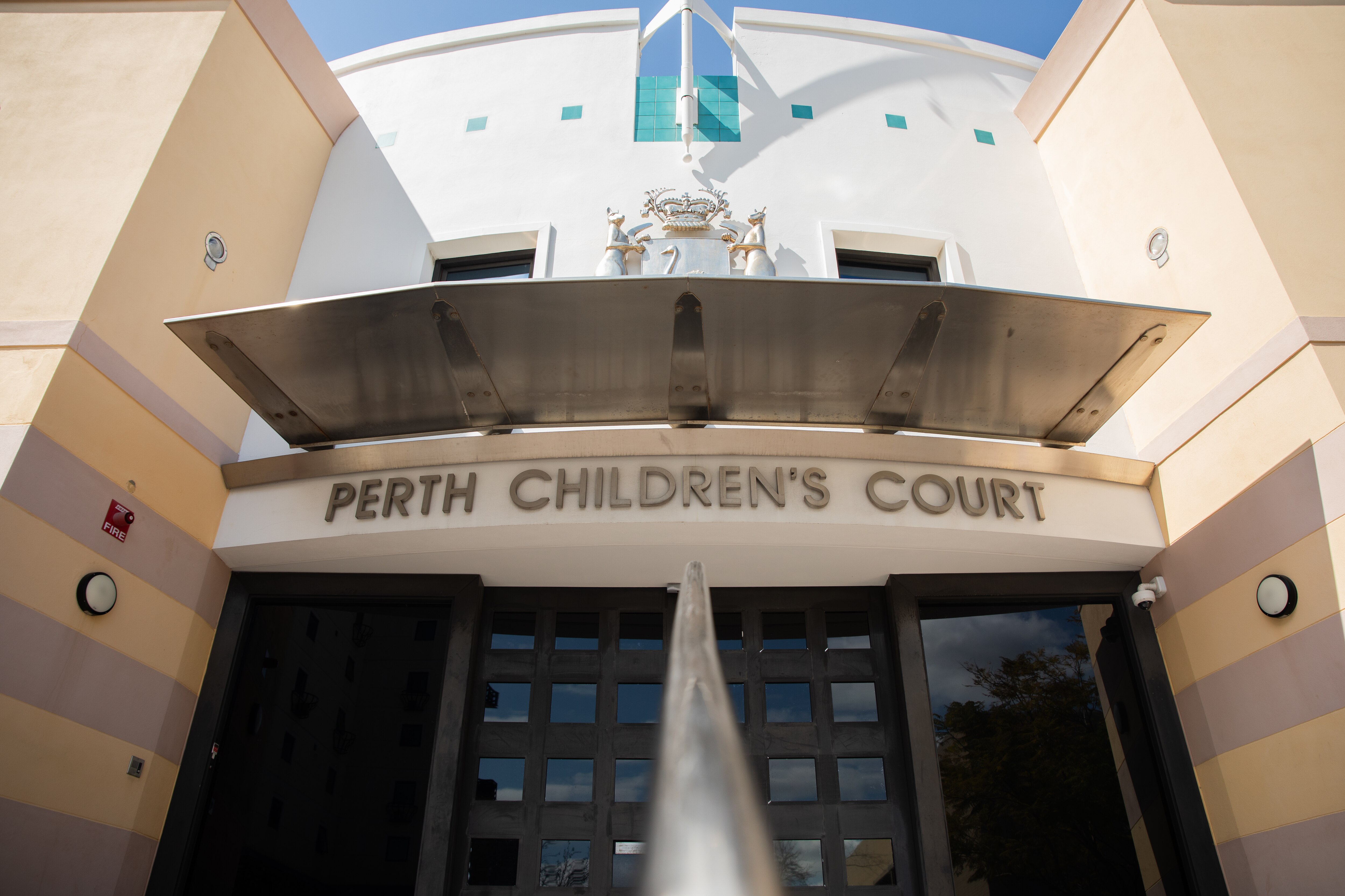La entrada a un edificio con las palabras 'Perth Children's Court' sobre las puertas principales.