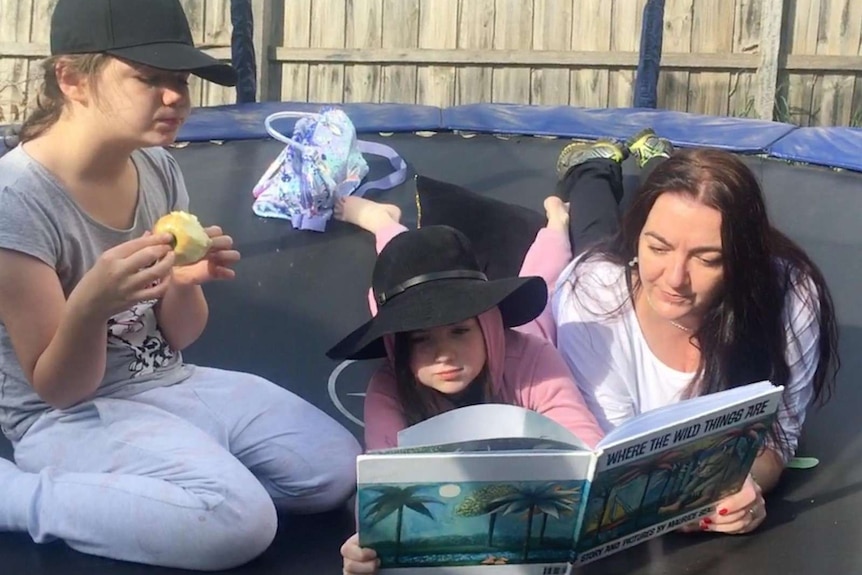 Tasmanian mum Kylie Pearson with her daughters on a trampoline.