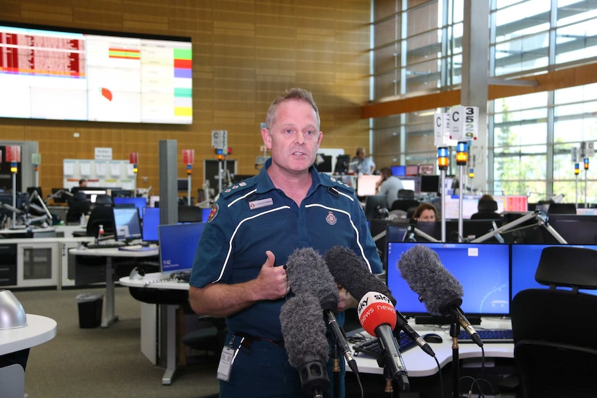 A man in ambulance uniform talks to the media