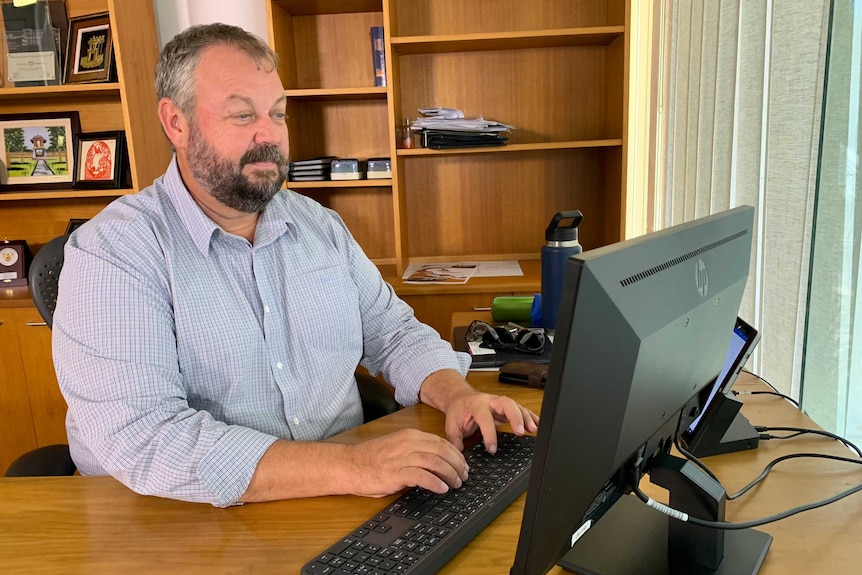 Greg Ireland sitting at his desk and typing on his computer.