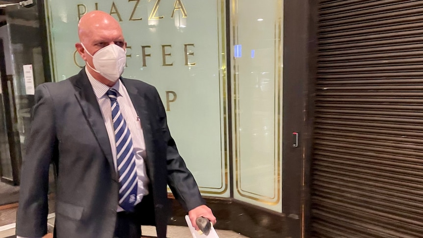 Man wearing mask walks out of court