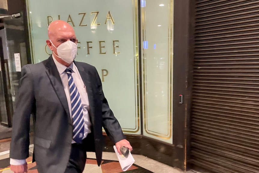 Man wearing mask walks out of court
