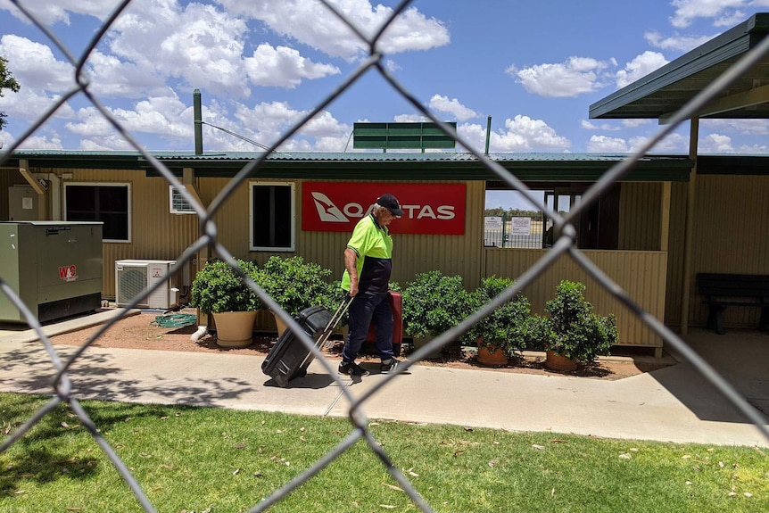 A man wheels luggage at Barcaldine airport.