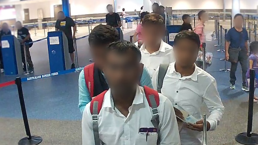 Four men, faces blurred, in an immigration queue at Brisbane Airport