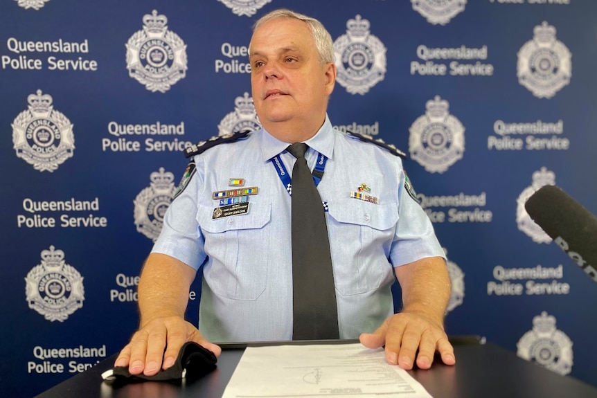 A police officer sits with his hands resting on a table