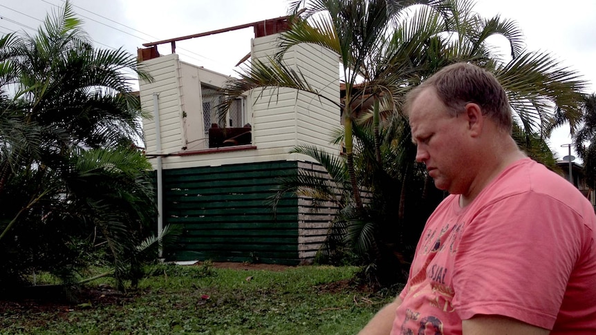 Shane Fayer sits in front of storm-damaged house