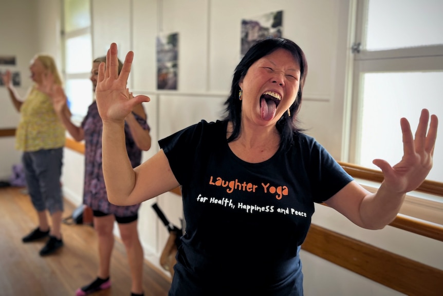 Laughter yoga leader Po Mei Kwong with hands up and tongue out, laughing