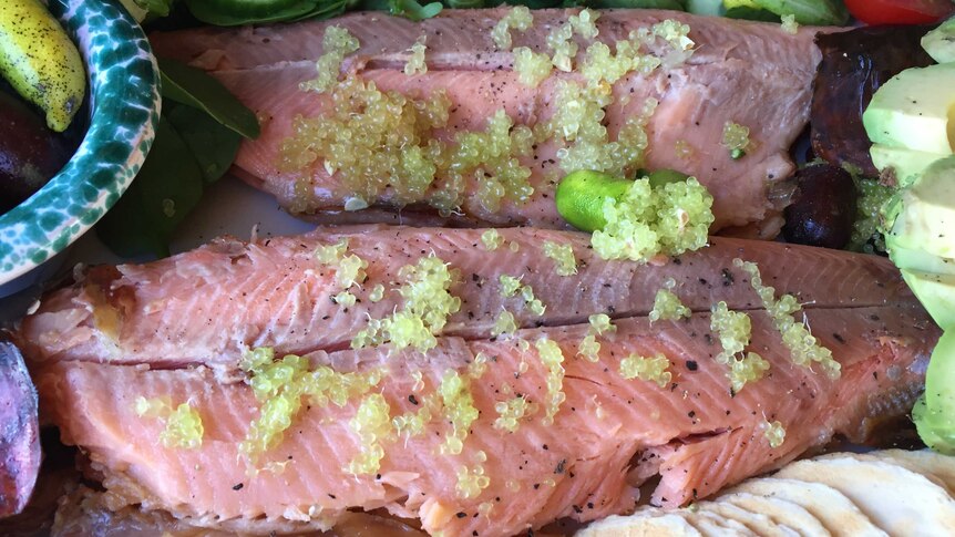 Finger lime caviar on a plate of salmon and salad