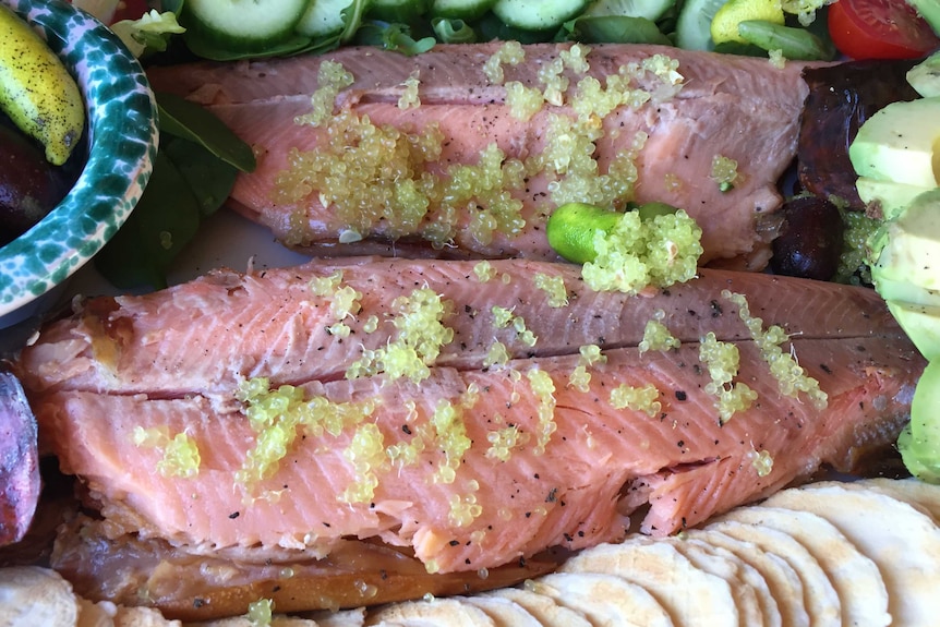 Finger lime caviar on a plate of salmon and salad