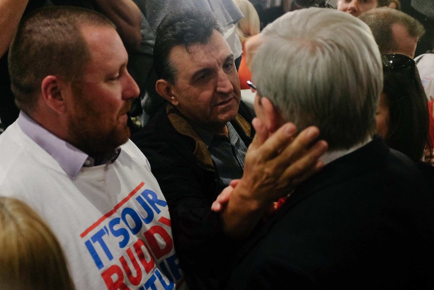 A Labor supporter consoles Kevin Rudd as he leaves after conceding defeat.