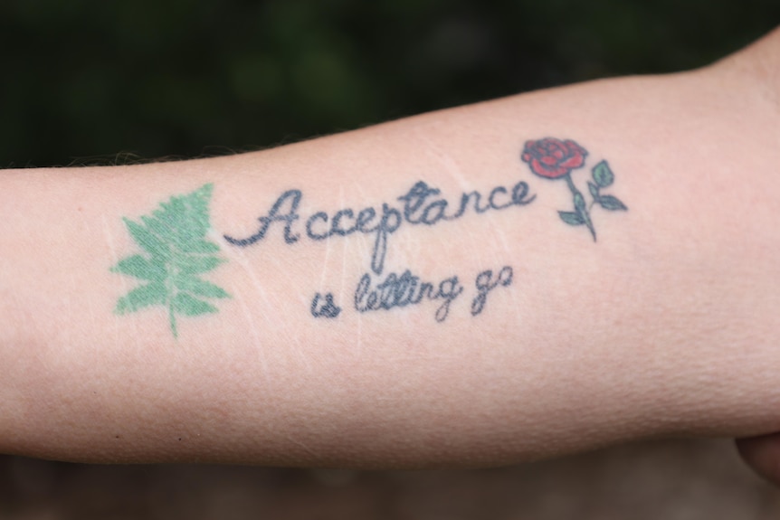 A woman's arm with a tattoo saying "acceptance and letting go"
