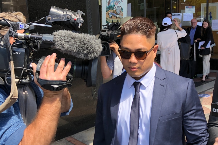 A man in a suit surrounded by journalists