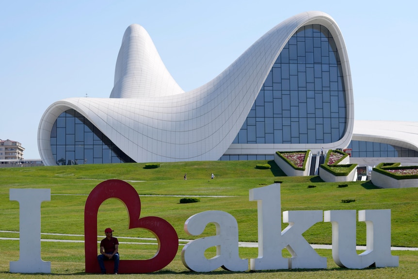 A man rests in an "I {heart} Baku" sign