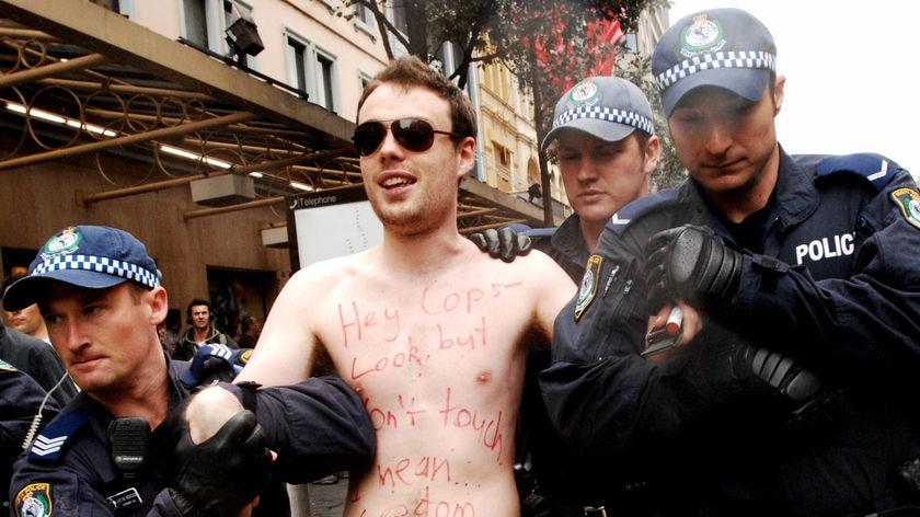 A naked protester is led away by police during the Stop Bush rally in Sydney.