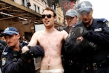 A naked protester is led away by police during the Stop Bush rally in Sydney.