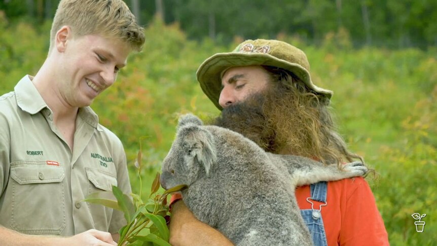 Robert Irwin with Costa holding a koala.