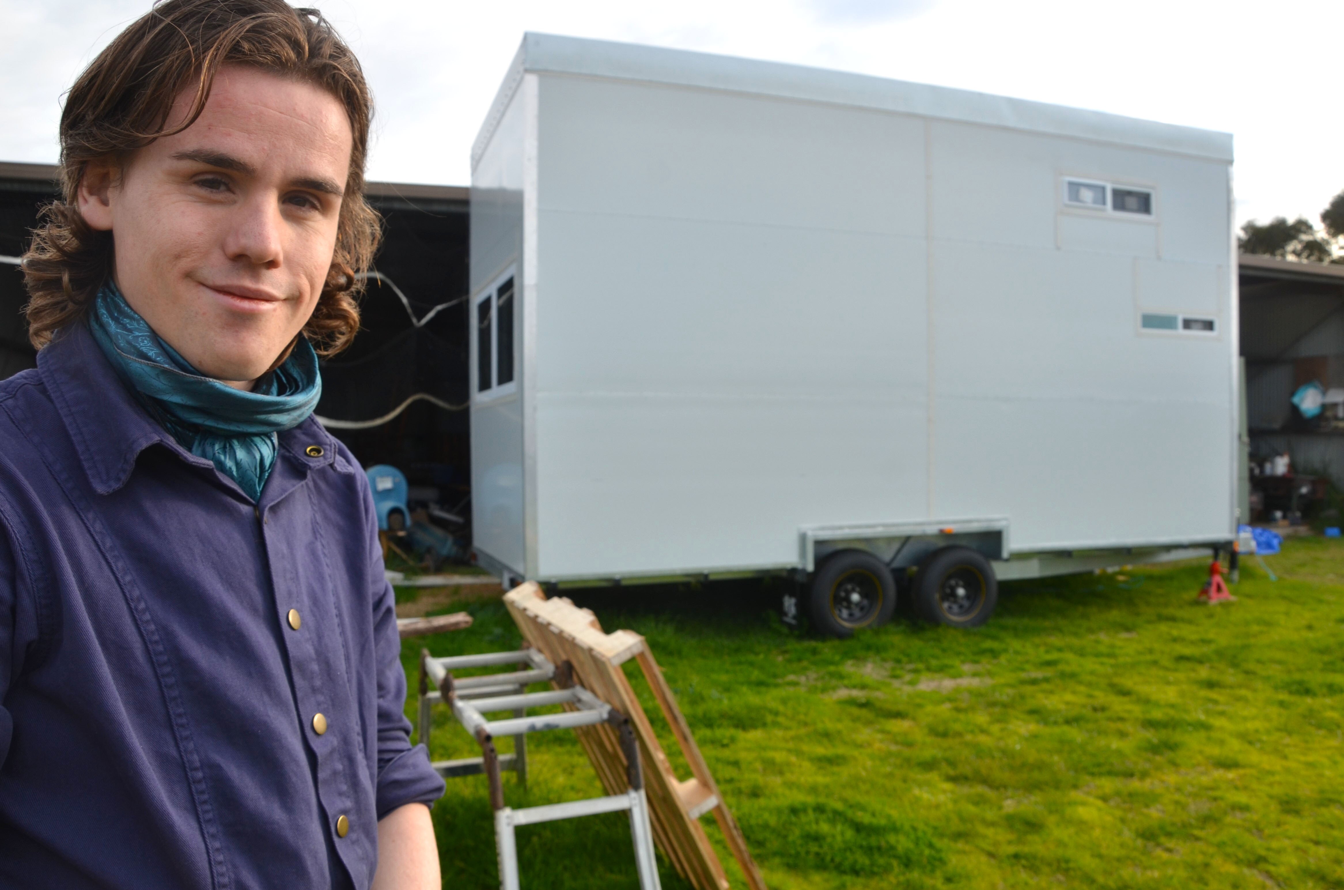 Person standing in front of a tiny house.