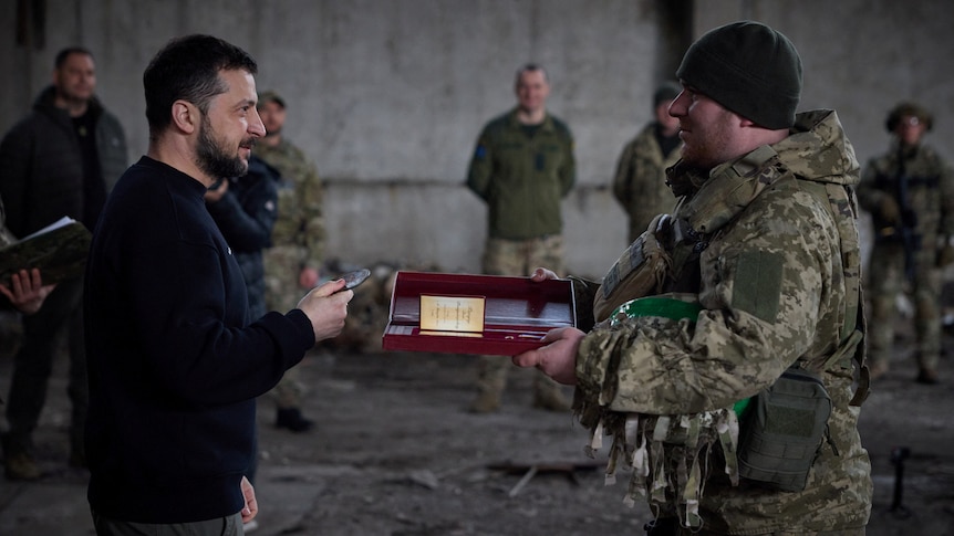 President Zelenskyy (left) awards a medal to a soldier.