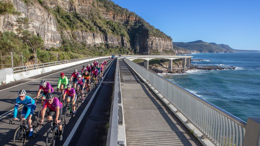 Cyclists ride across the sea cliff bridge north of Wollongong