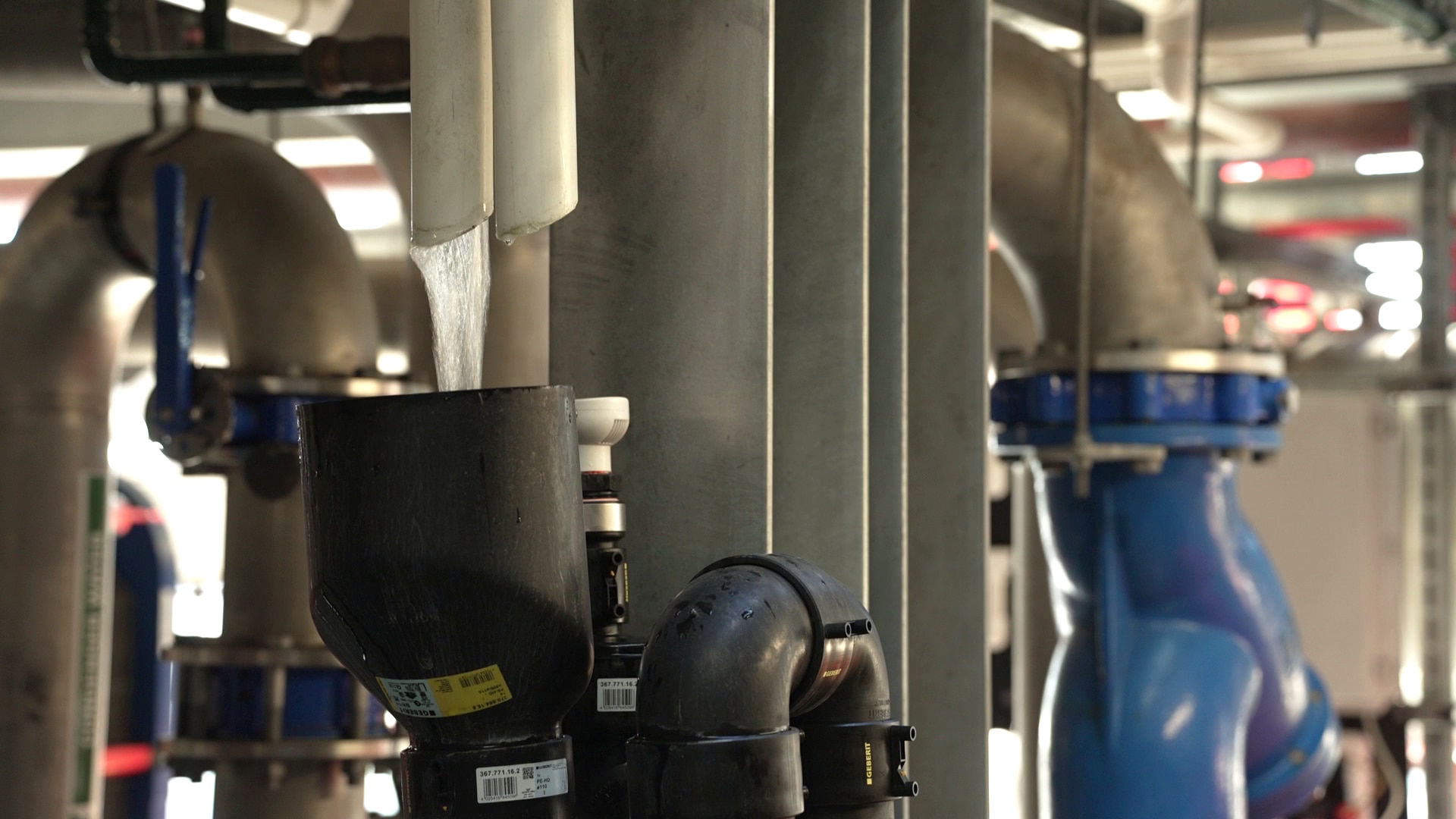 Water runs through a small PVC pipe into a catchment inside a large evaporative cooling system in a data centre.
